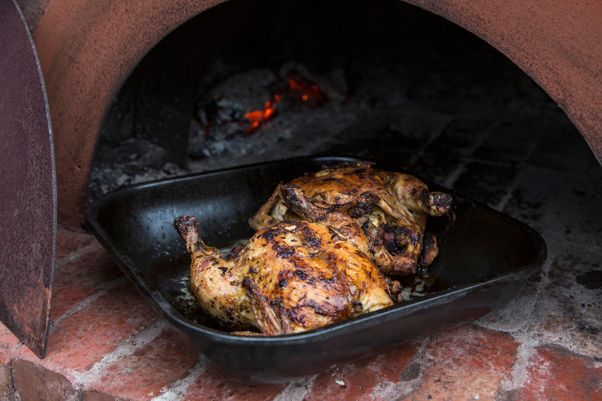 Chicken being roasted in a traditional brick oven / Getty