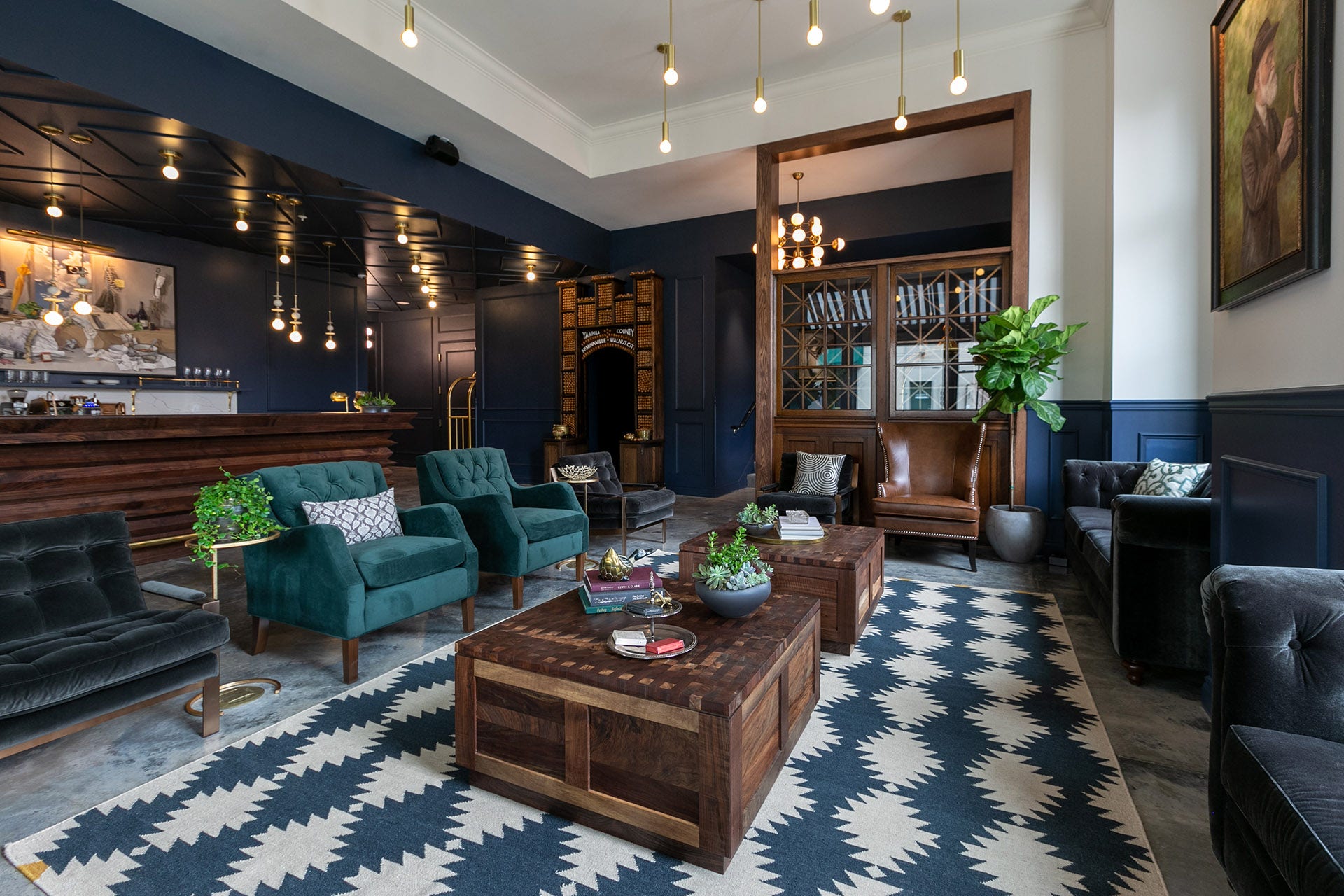 Dark blue interior with dark wood, velvet seating and a blue and white patterned rug