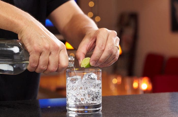 Hands squeezing lime and pouring vodka