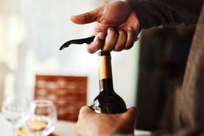 close up on hands opening a wine bottle